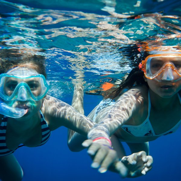 Deux jeunes en randonnée palmée, masques colorés et sourires sous l'eau, découverte de la mer en famille à Villefranche