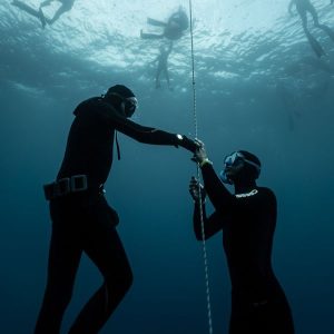 Instructeur d'apnée guidant un élève au câble sous l'eau à Villefranche-sur-Mer, accompagnement coaching bienveillant et sécurisé